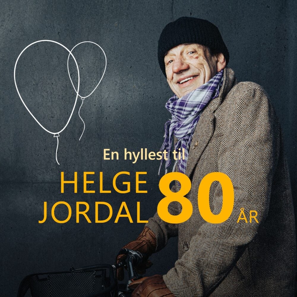 En eldre mann i frakk, skjerf og hatt smiler ved siden av to tegnede ballonger, med teksten "En hyllest til Helge Jordal 80 år" mot en mørk bakgrunn.