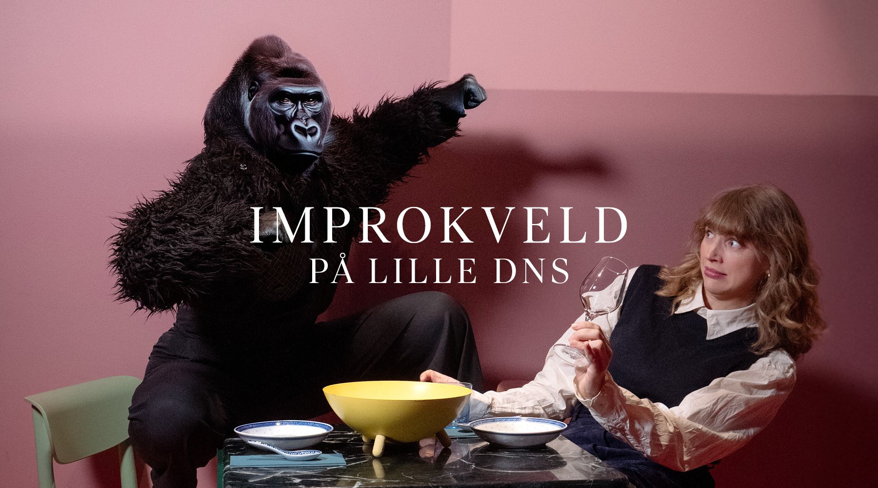 En person i gorilladrakt sitter ved siden av en kvinne som holder et vinglass ved et bord med servise. Teksten lyder "IMPROKVELD PÅ LILLE DNS.