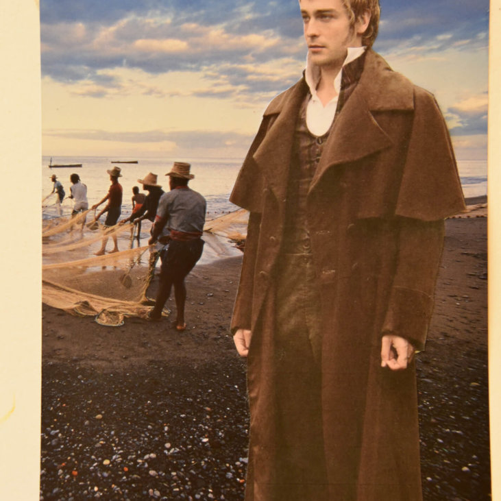 En mann i vintageklær står på en strand. Flere personer i bakgrunnen drar inn et nett fra havet. Himmelen er delvis overskyet, og en båt er synlig på vannet.