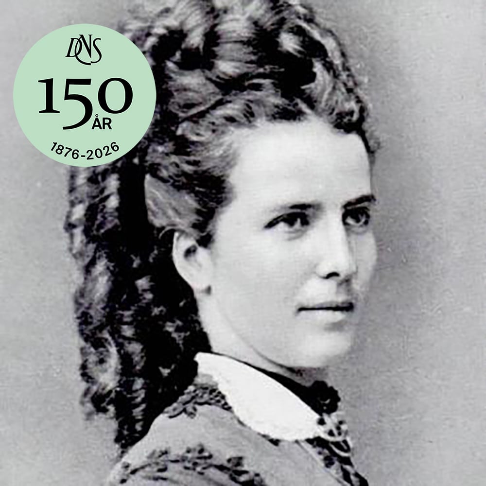 Svart-hvitt portrett av en kvinne med krøllete hår; i en grønn sirkel øverst til venstre står det "DNS 150 ÅR 1876-2026.