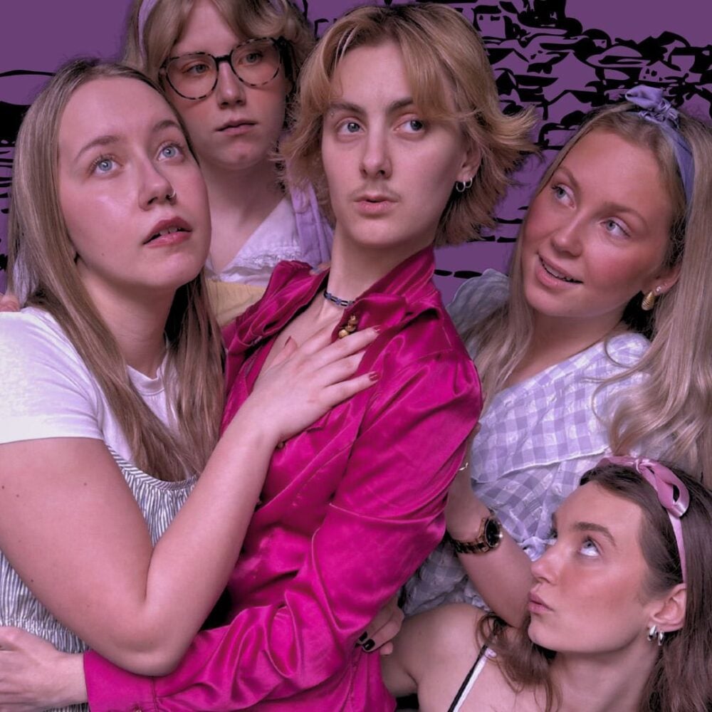 Fem personer poserer tett sammen og ser i ulike retninger, med en lilla illustrert bakgrunn bak dem. Den sentrale figuren har på seg en knallrosa skjorte.