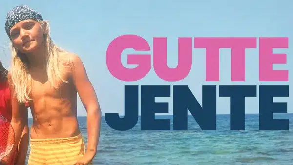 Et langhåret barn i gule shorts står ved sjøen med stor tekst «GUTTE JENTE» i rosa og blått over himmelbakgrunnen.