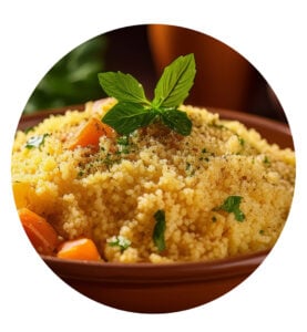 En bolle med couscous pyntet med friske urter og blandet med grønnsaker, servert i et brunt fat.