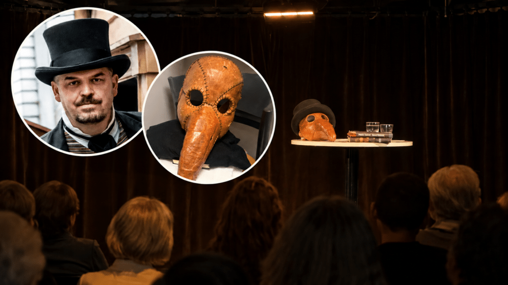 En mann med høyhatt, en person med en pestlegemaske og den samme masken og hatten på et bord vises frem for publikum i et svakt opplyst rom.