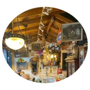 Rom med tretak, lysekroner og vegger dekorert med ulike malerier, klokker, hyller, hatter og eklektiske vintageartikler.